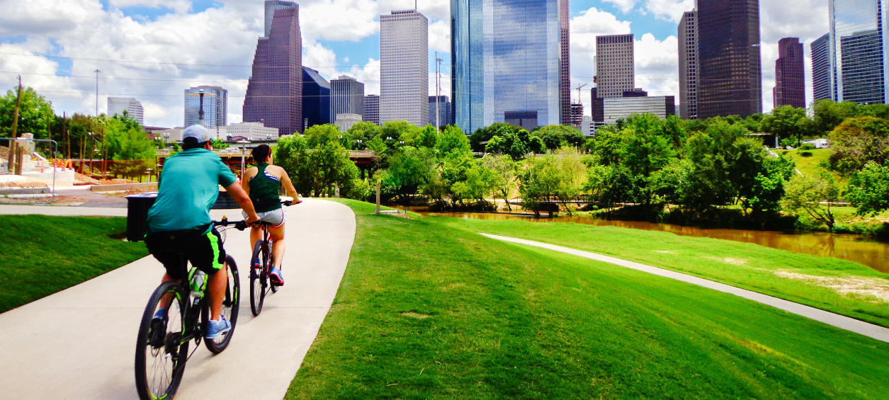 Couple riding through a park with Houston skyscrapers in background