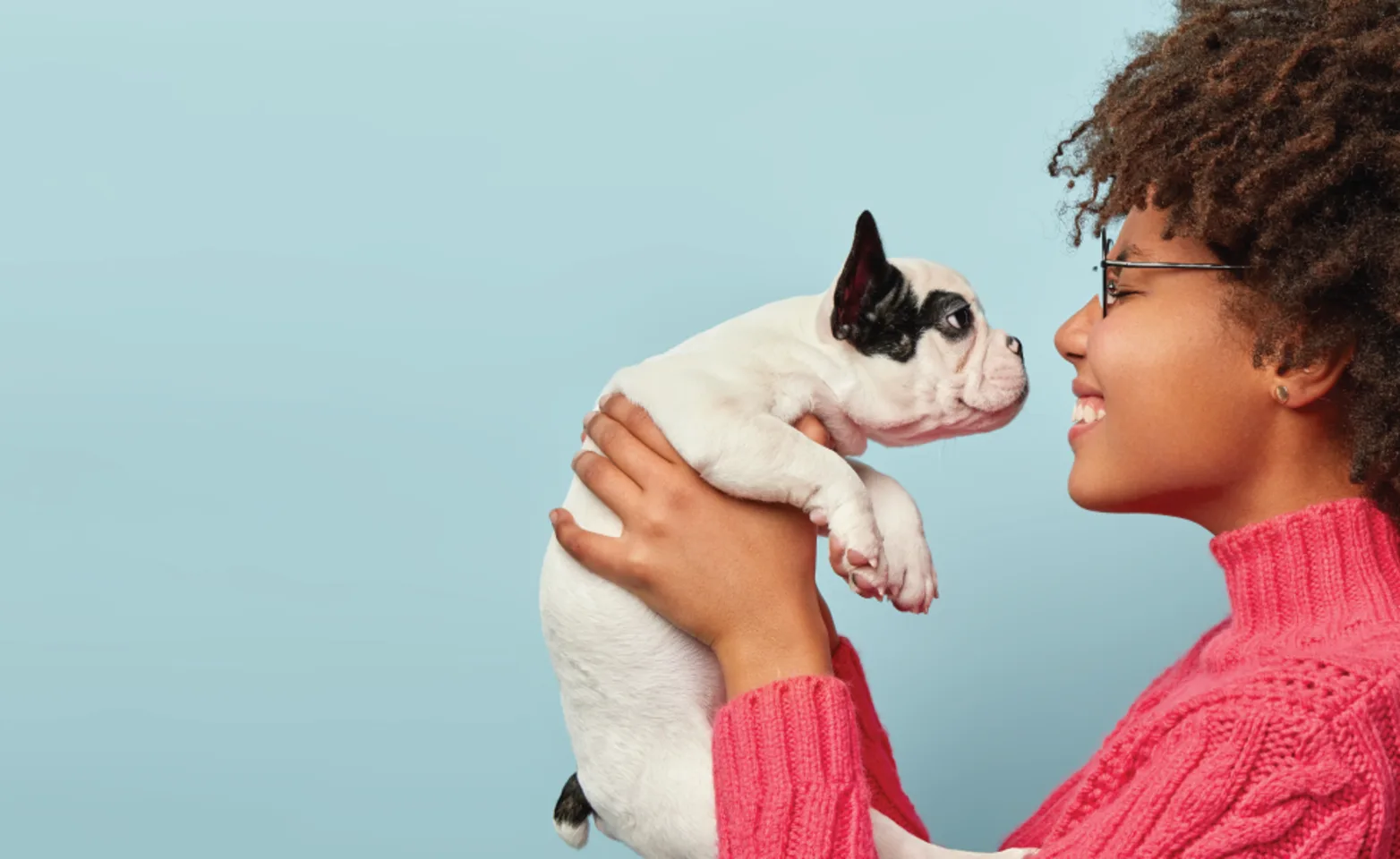 Woman holding dog on light blue background