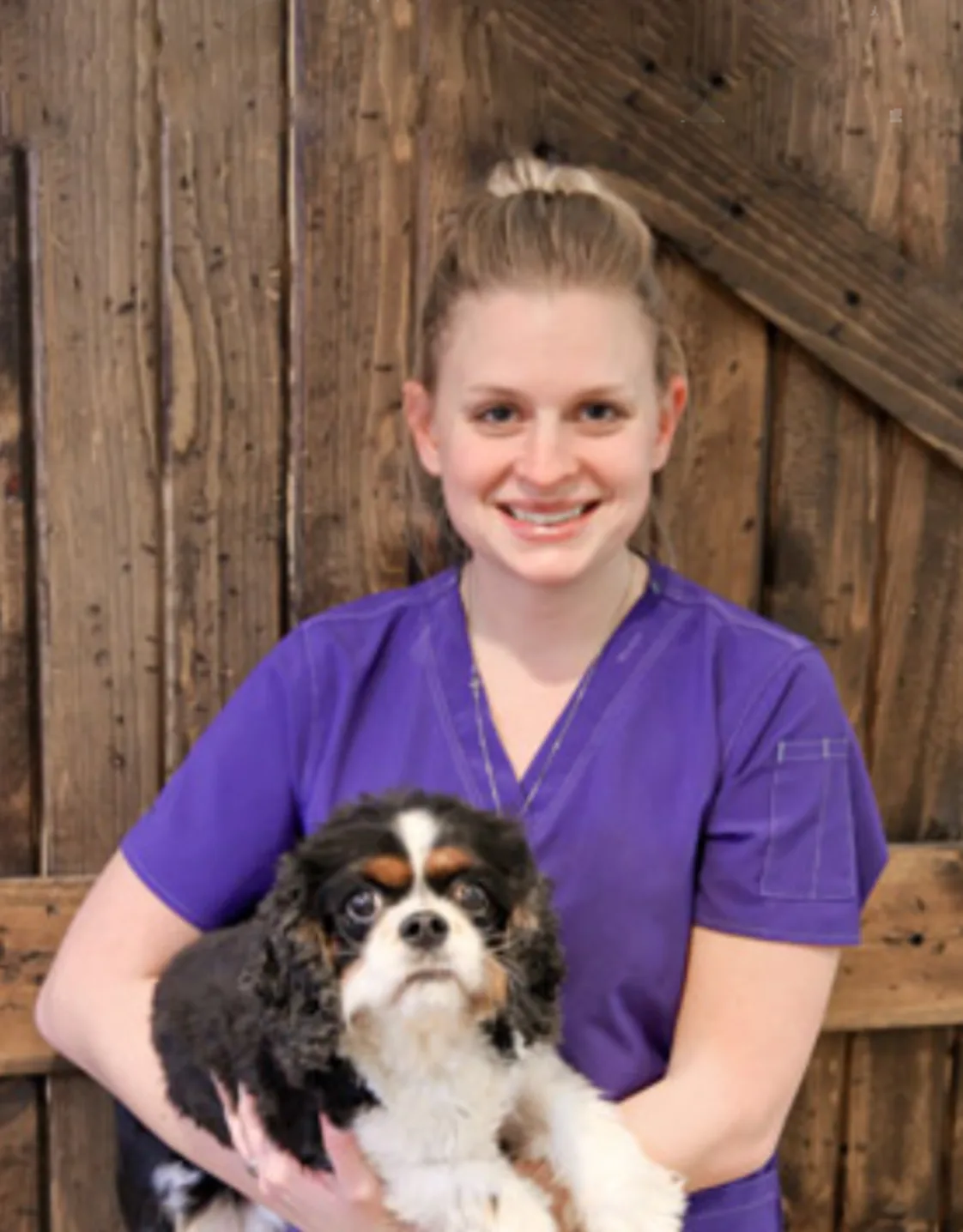 A veterinarian posing with a black and white dog A veterinarian posing with a black and white dog