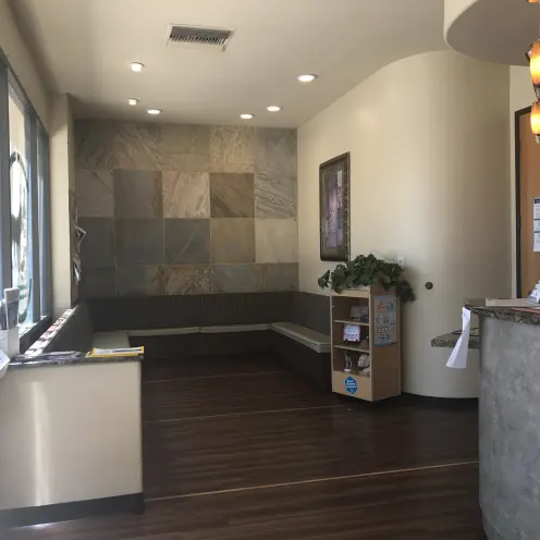 Telegraph Canyon Animal Medical Center's lobby area which consist of wrap around cushioned bench, flyers, magazine table and picture on the wall