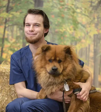 Brandon holding a fluffy orange Chow dog in his arms