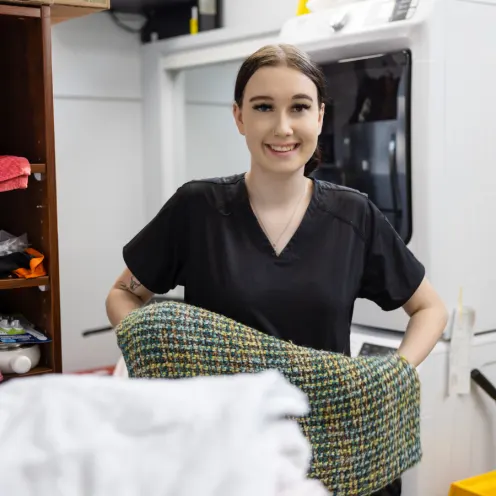Staff member folding a blanket and smiling at the camera