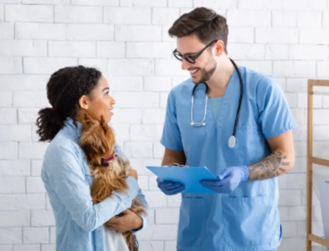 Veterinarian Talking to Client Holding Her Dog Veterinarian Talking to Client Holding Her Dog