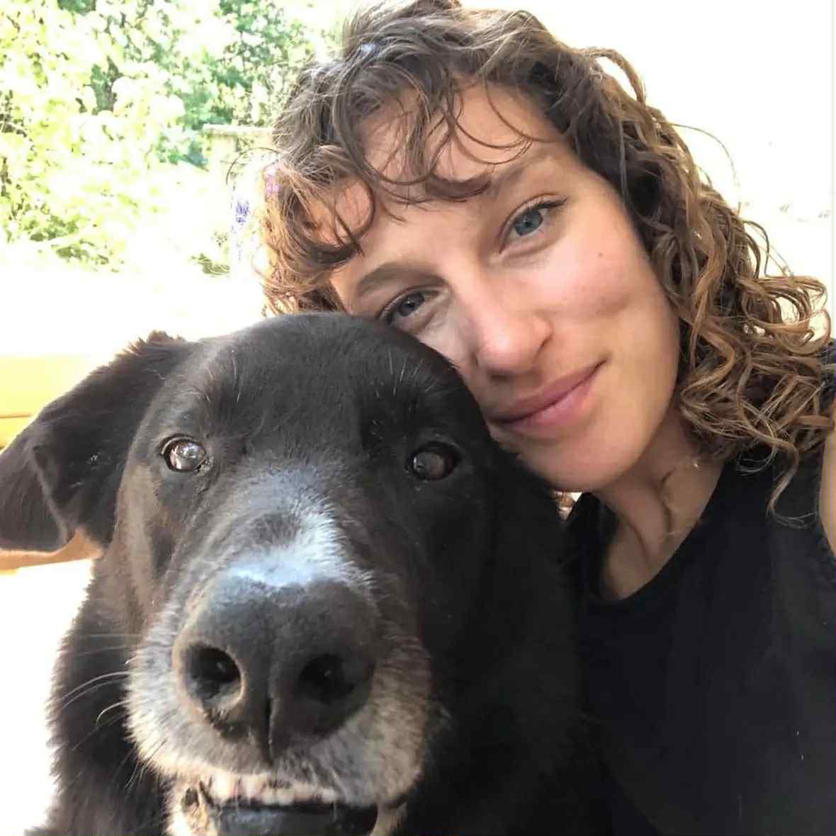 Hilary Strongs smiling next to a black and white dog.