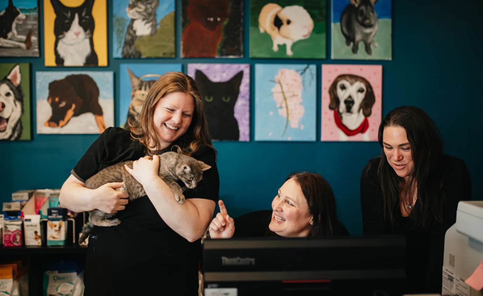 Three staff ladies at the front desk and one is holding a cat