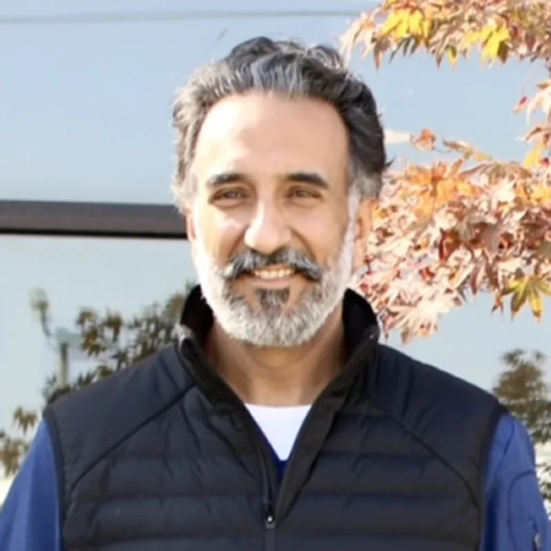Man with a black vest and blue shirt smiling at camera Man with a black vest and blue shirt smiling at camera