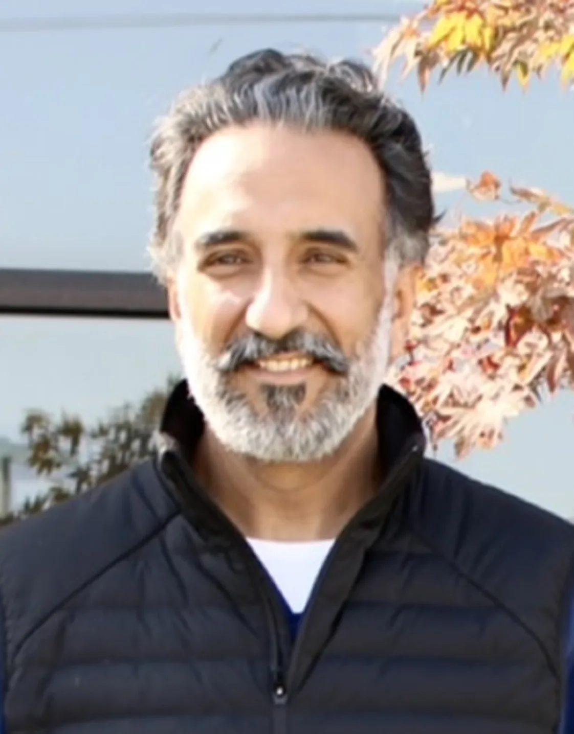 Man with a black vest and blue shirt smiling at camera Man with a black vest and blue shirt smiling at camera