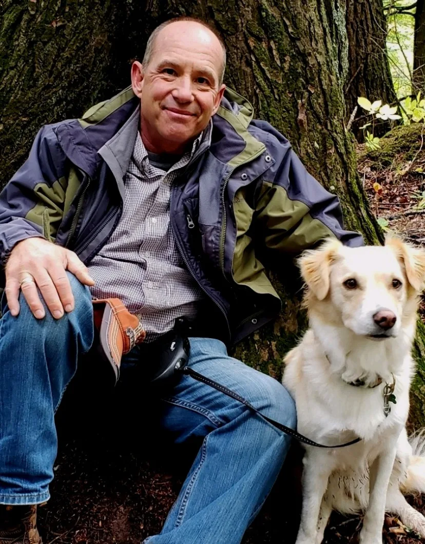 Dr. Dale Covy with white dog in front of a tree