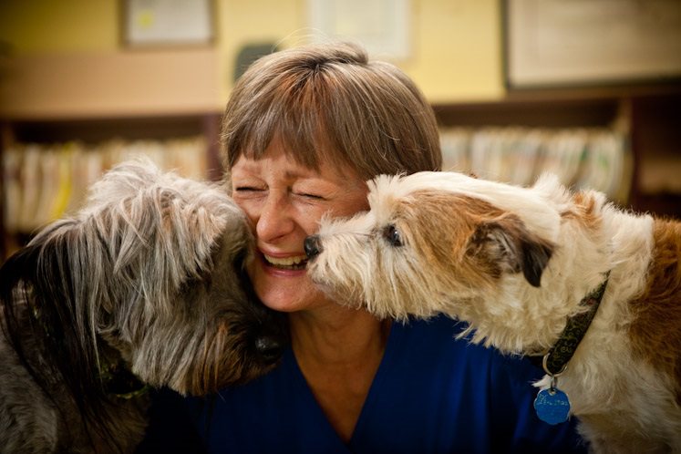 Woman smiling in between two dogs.
