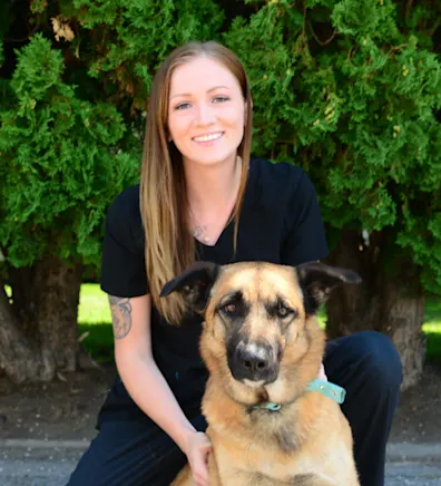 Cheyenne holding a dog and sitting in front of the Eastside sign