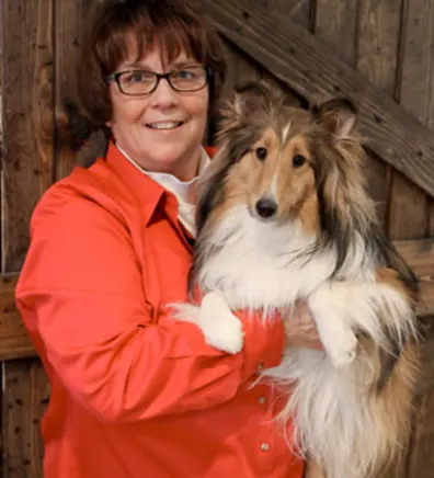 A veterinarian posing with a brown and white dog A veterinarian posing with a brown and white dog