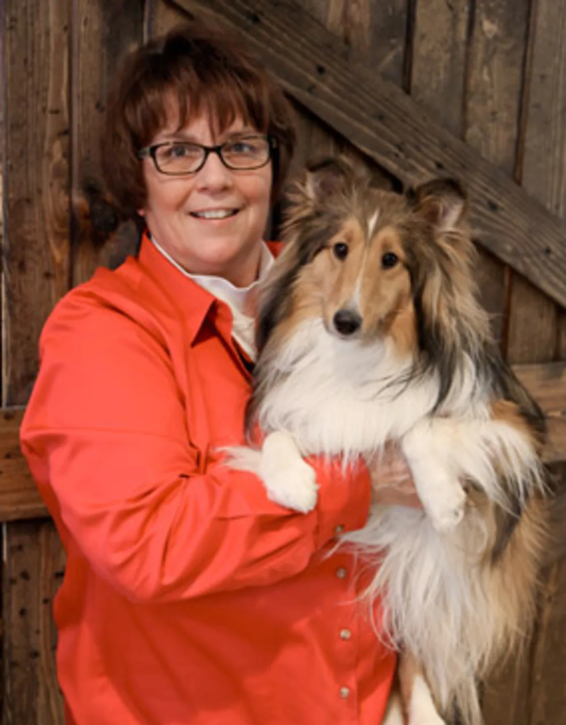 A veterinarian posing with a brown and white dog A veterinarian posing with a brown and white dog