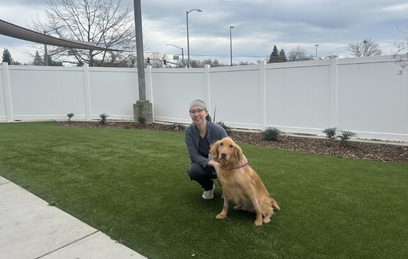Staff sitting on grass with golden retriever