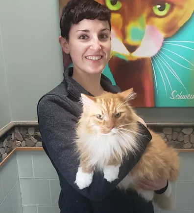 Rebecca Walker in dark clothes while holding a large long haired yellow tabby cat. Rebecca Walker in dark clothes while holding a large long haired yellow tabby cat.