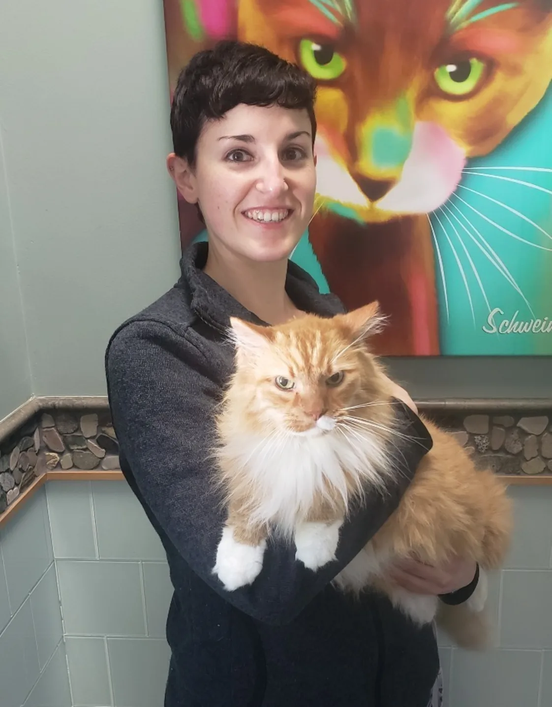 Rebecca Walker in dark clothes while holding a large long haired yellow tabby cat. Rebecca Walker in dark clothes while holding a large long haired yellow tabby cat.