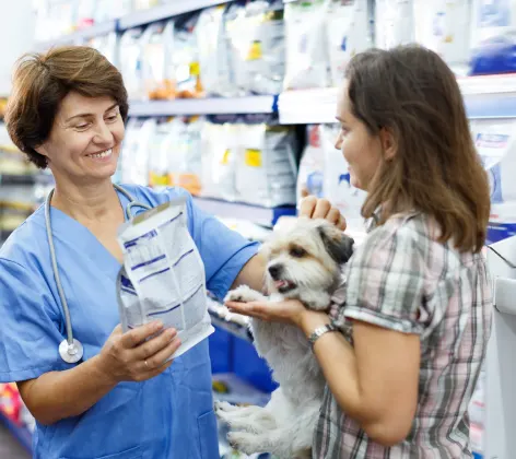 Woman giving prescription food to customer and dog 