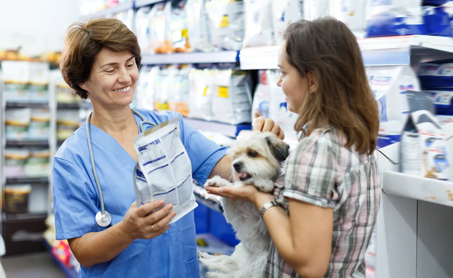 Woman giving prescription food to customer and dog Woman giving prescription food to customer and dog