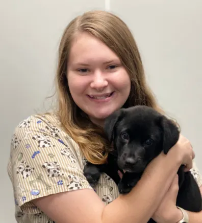 Layla Davis holding a small puppy with short black fur
