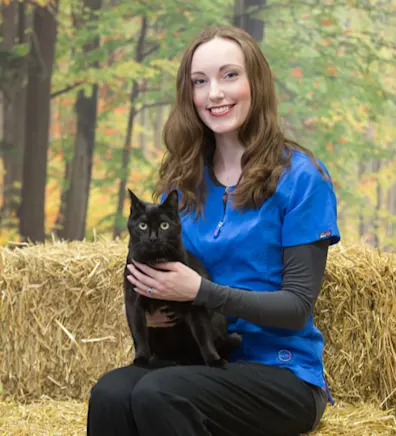 Laura sitting on hay and holding a black cat