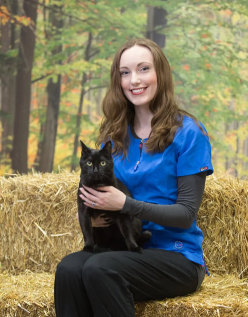 Laura sitting on hay and holding a black cat
