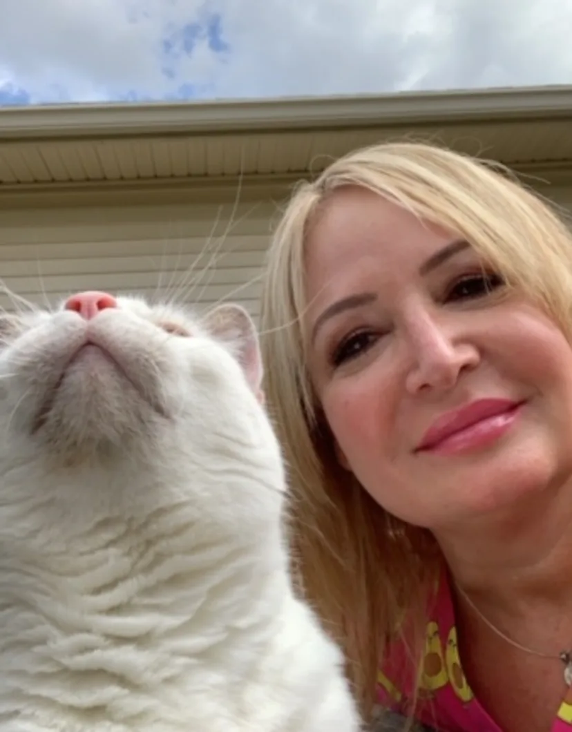 Staff photo from Niles Veterinary Clinic of Linda P. taking a selfie of her and her white cat outside.