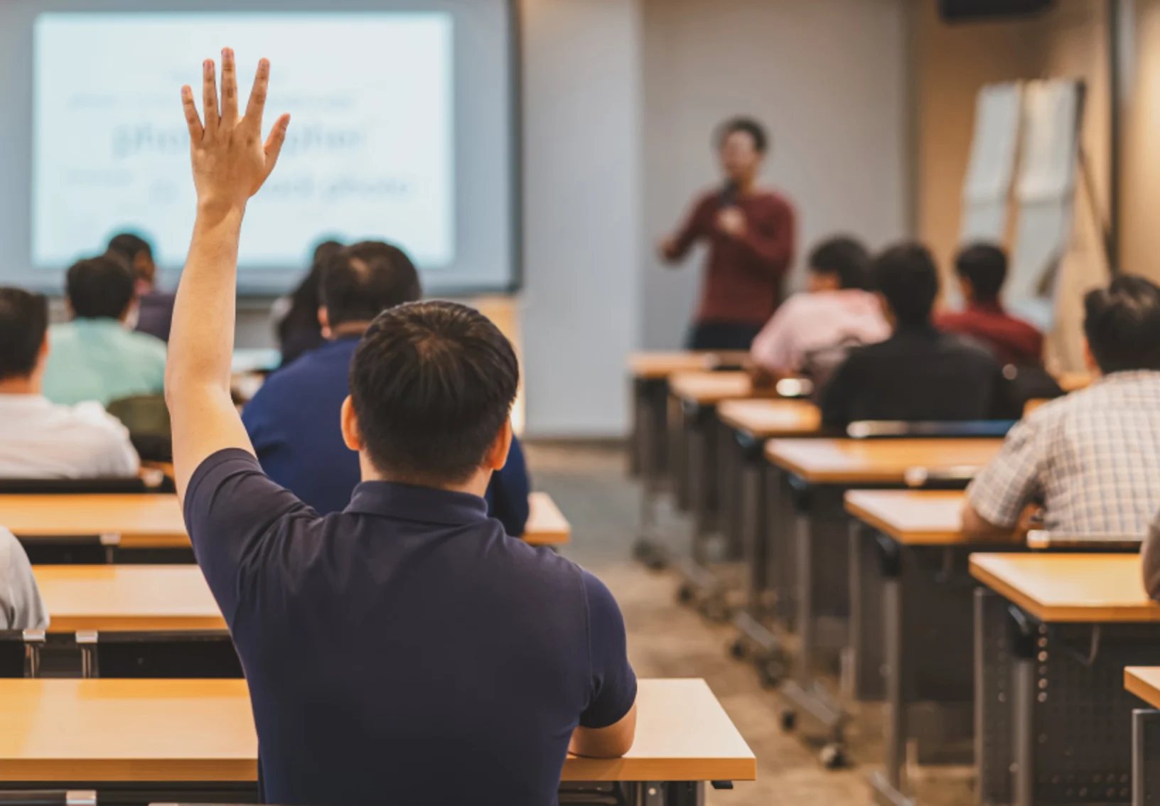 Student raising hand in class Student raising hand in class
