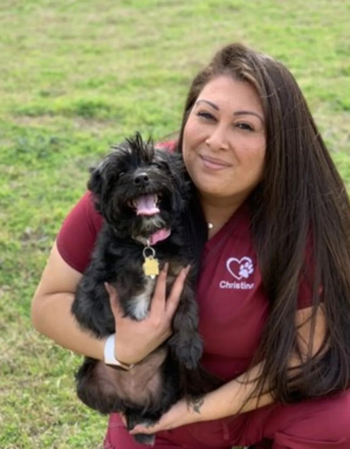 Photo of Christina Balderas holding black dog in the grass Photo of Christina Balderas holding black dog in the grass