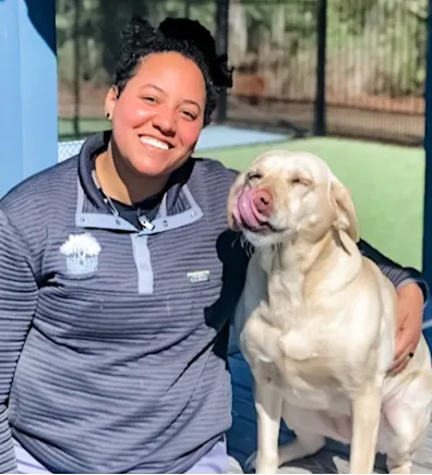 Taylor Anthony smiling kneeling down hugging a white large puppy Taylor Anthony smiling kneeling down hugging a white large puppy