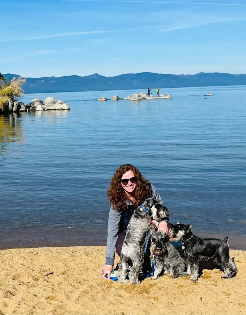 Rebecca Conway with two small black dogs and a giant, furry, white dog.