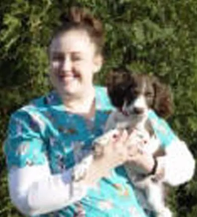 Jana's staff photo from Stillwater Veterinary Clinic posing with her little poodle outside.