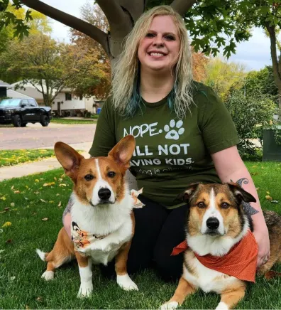 Abby's staff photo from Heather Ridge Pet Hospital where she is holding her black and white cat with her two black and white dogs on each side of her.