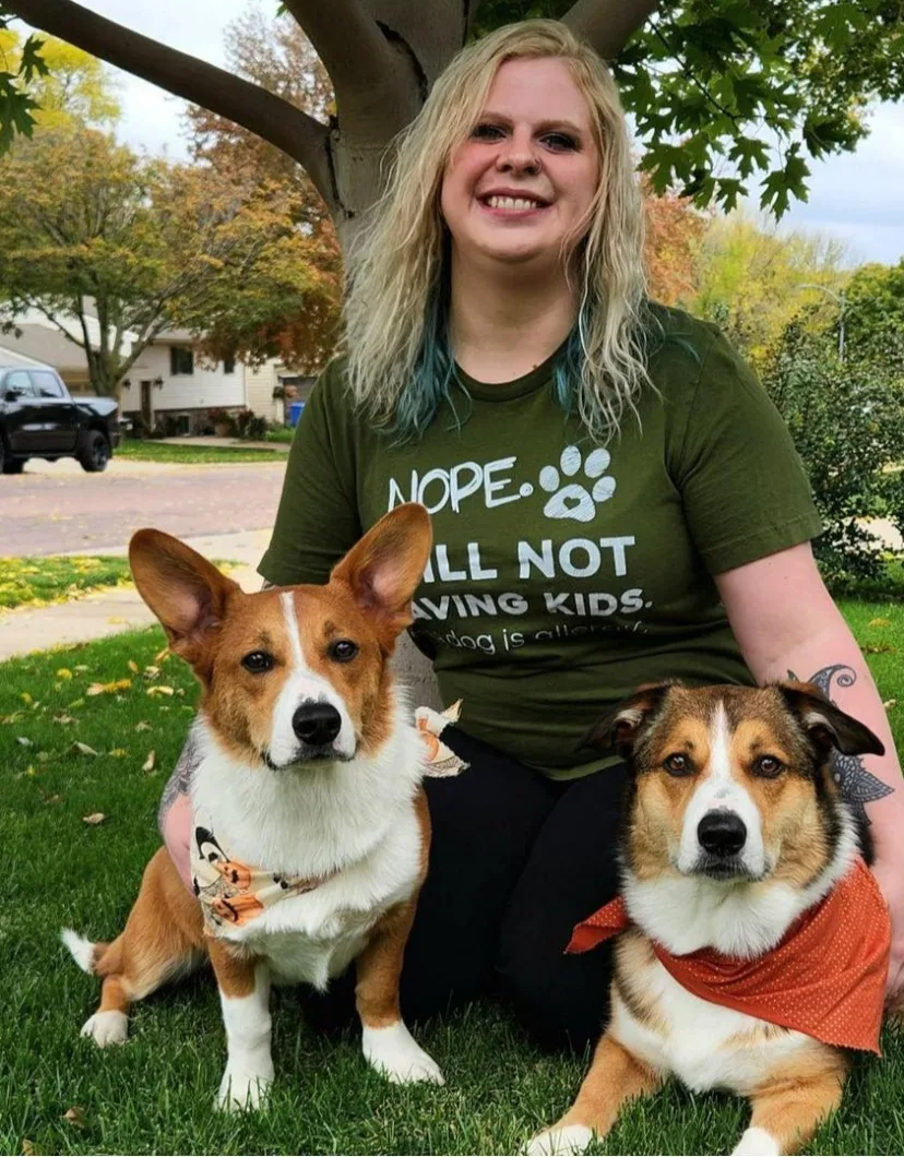 Abby's staff photo from Heather Ridge Pet Hospital where she is holding her black and white cat with her two black and white dogs on each side of her.