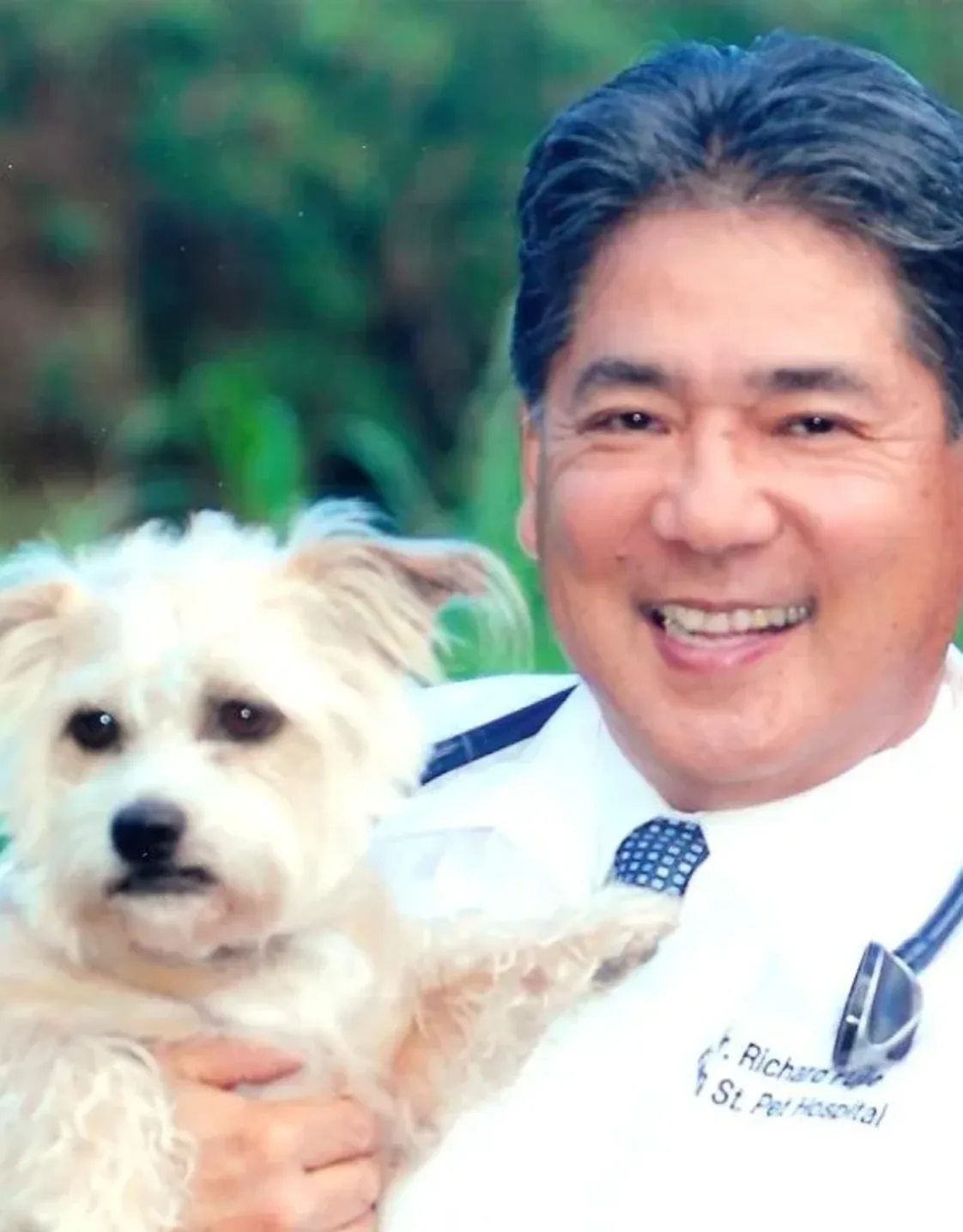 Dr. Richard Fujie holding up a white dog Dr. Richard Fujie holding up a white dog