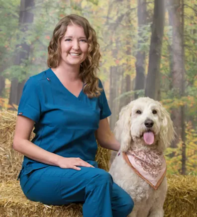 Michelle sitting next to a fluffy white dog with a pink bandana on