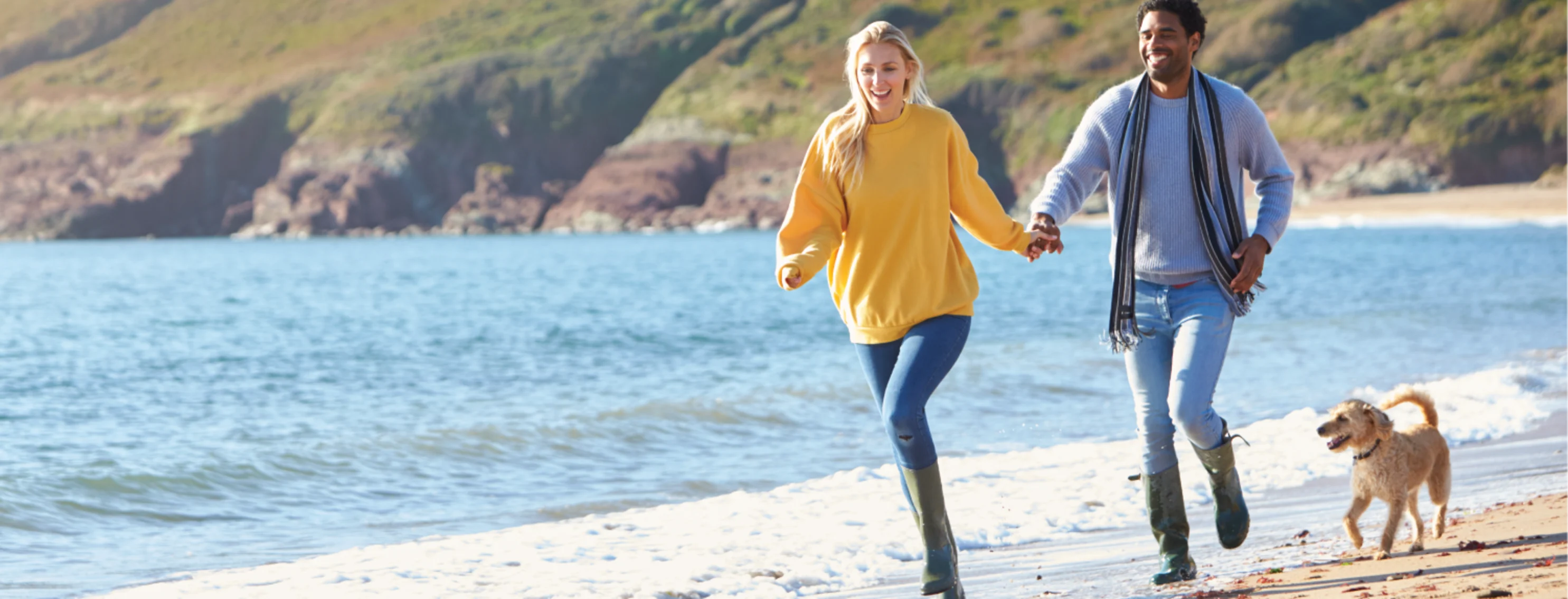 Couple running on the beach with their dog