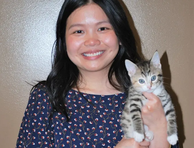 Dr. Maryse Arteficio smiling at the camera while holding a cat