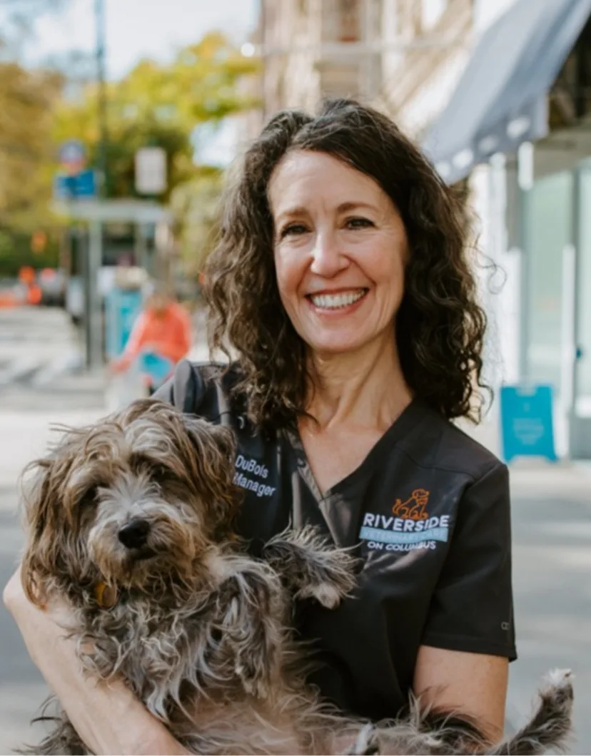 Aliza's staff photo from Riverside Animal Hospital South where she is smiling and holding her tabby orange cat and black dog.