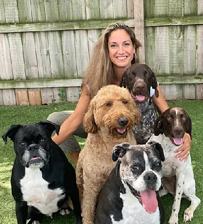 Leslie Shibovich, Multi-Site Practice Manager of Pet Experts Veterinary Group, sitting outside with 5 dogs.