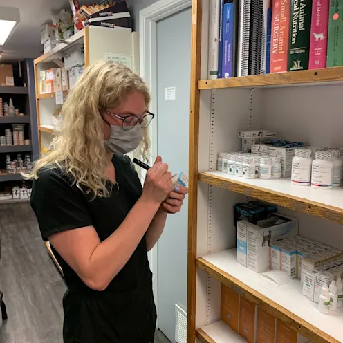 Staff writing into medications at clinic pharmacy Staff writing into medications at clinic pharmacy