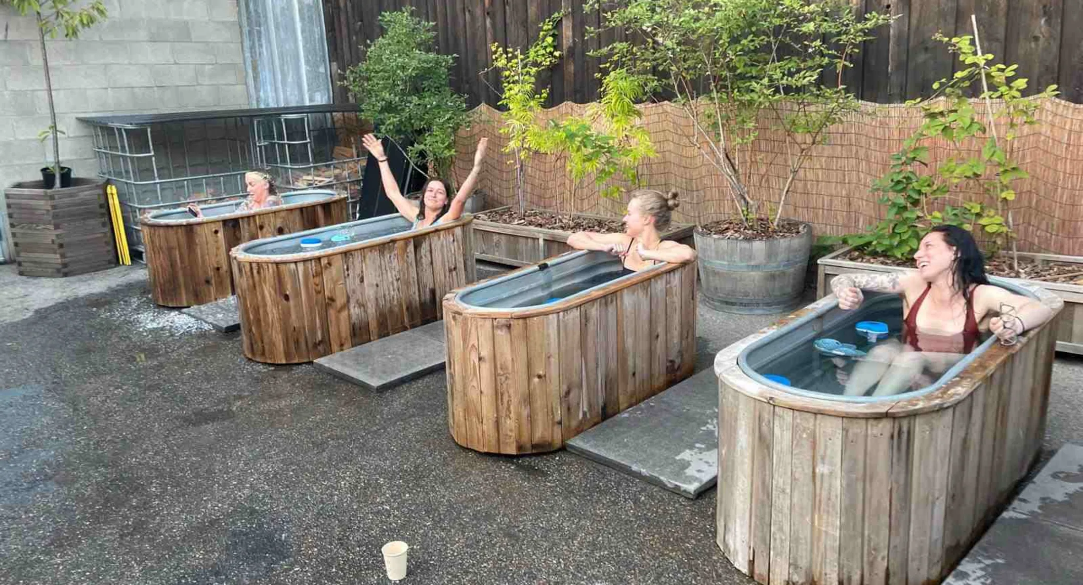 Staff cold plunging in metal tubs outside. Staff cold plunging in metal tubs outside.