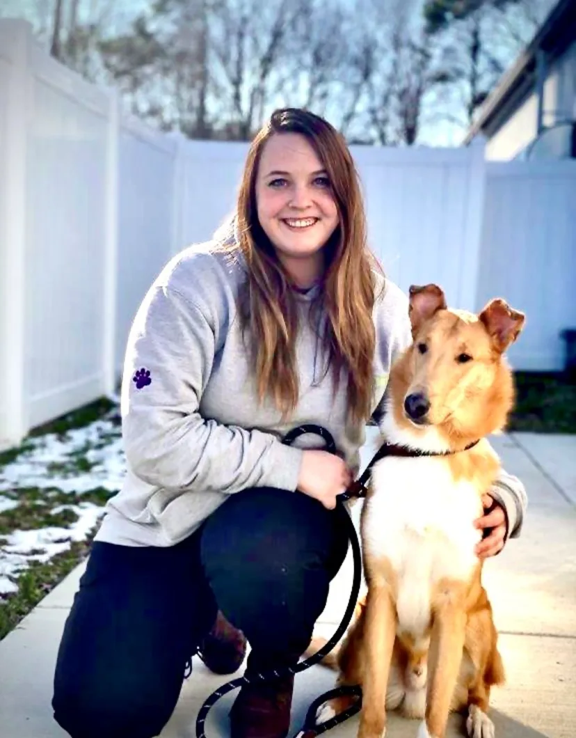 Woman posing on one knee next to her dog.