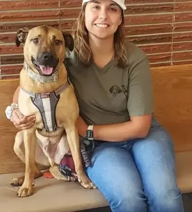 Kirsten smiling and hugging a dog. Kirsten smiling and hugging a dog.