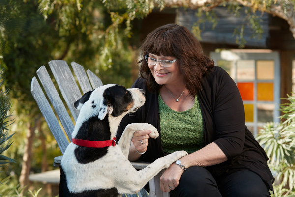 Woman shaking hands with spotted dog.