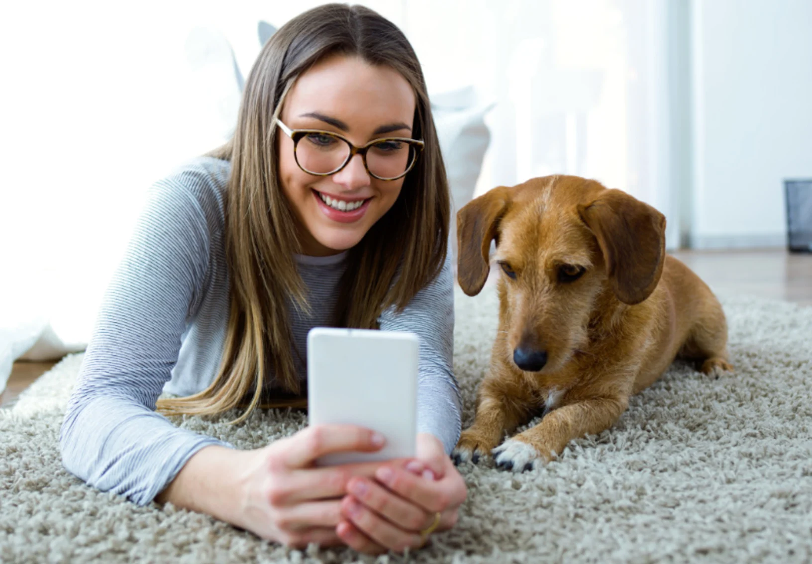 Girl on Phone with Dog Lying on Carpet
