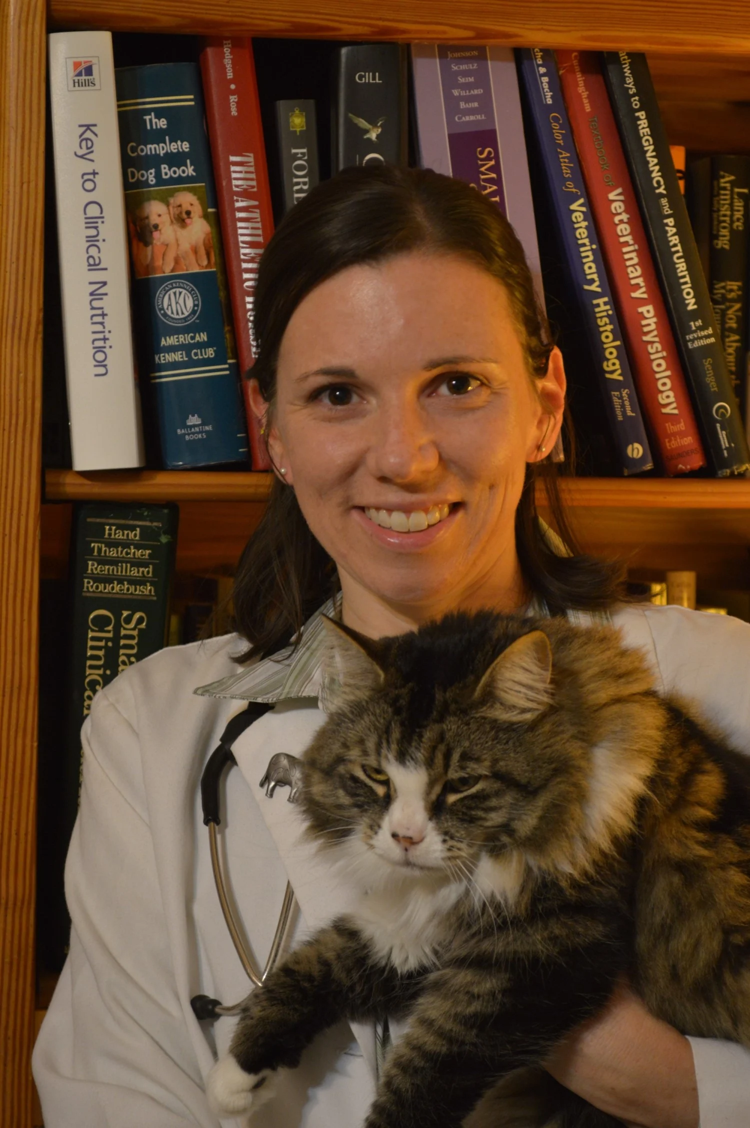 Chyrle Bonk DVM holding a cat in front of a bookcase.