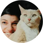 A human is posing with her white and orange cat looking so serious.