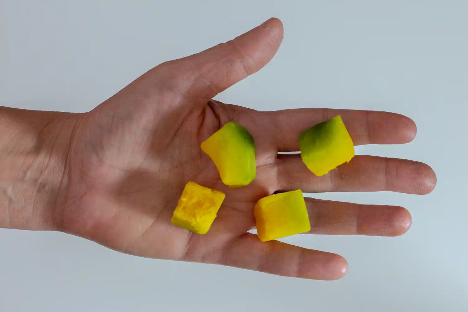 a hand holding four bite-sized pieces of cooked kabocha squash