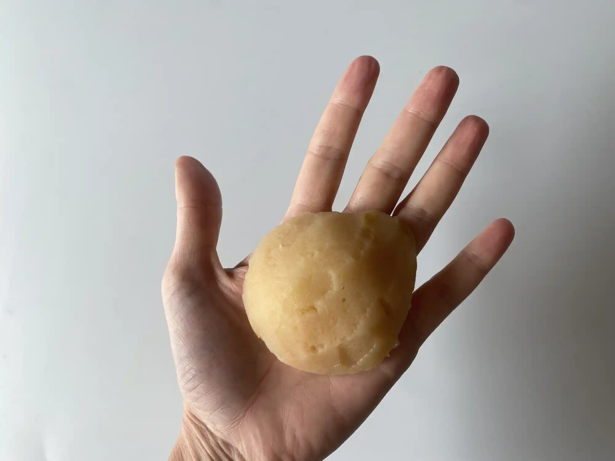a hand holding one large quince half that has been deseeded and cooked until soft