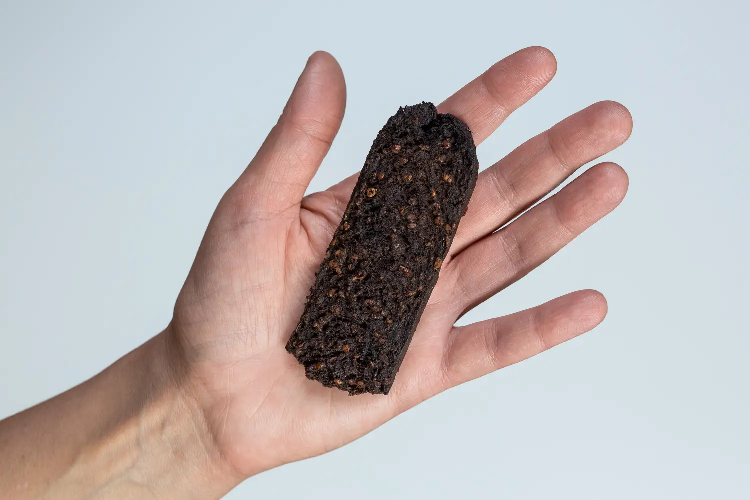 a hand holding a thin slice of blood sausage