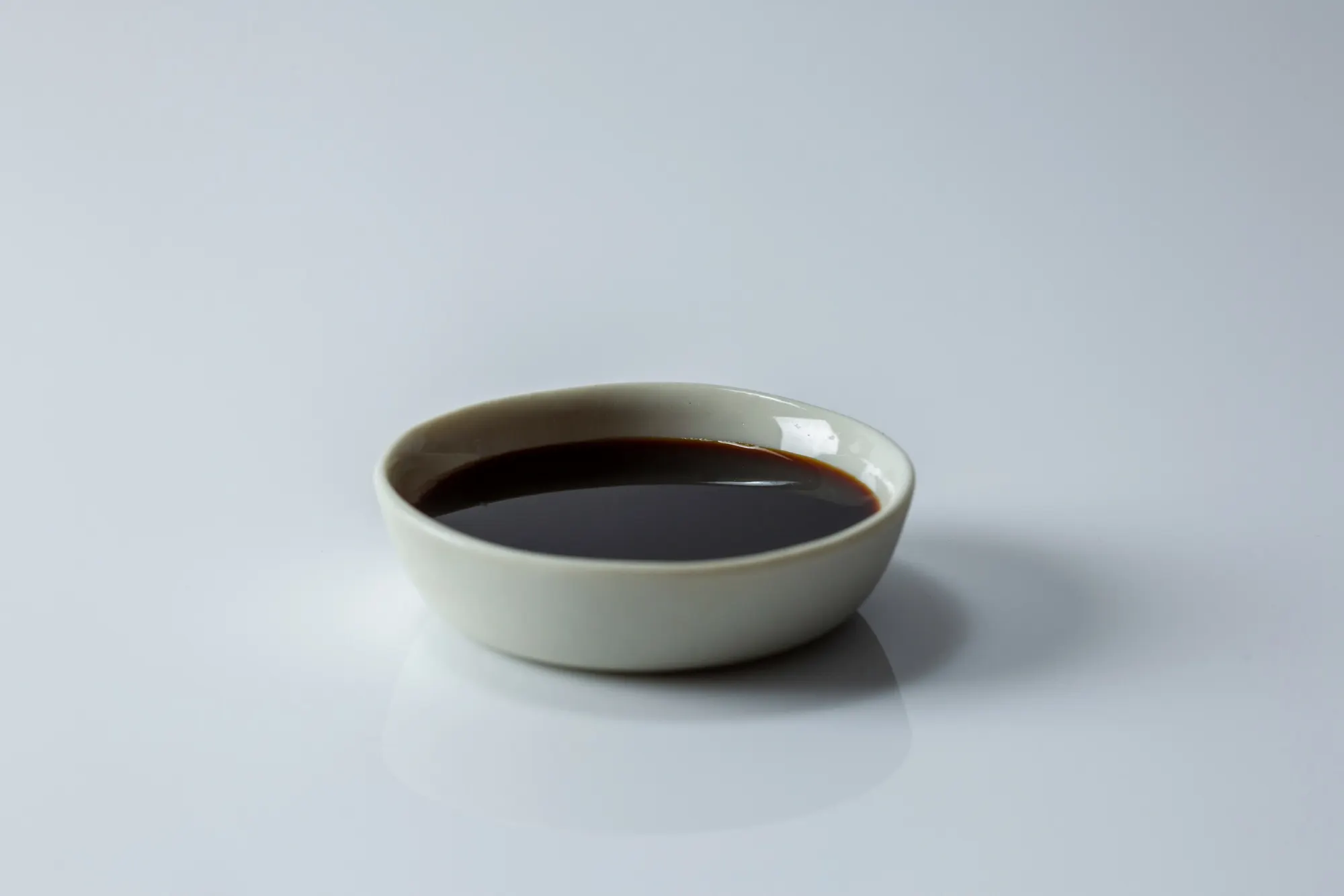 a small shallow ceramic bowl filled with soy sauce